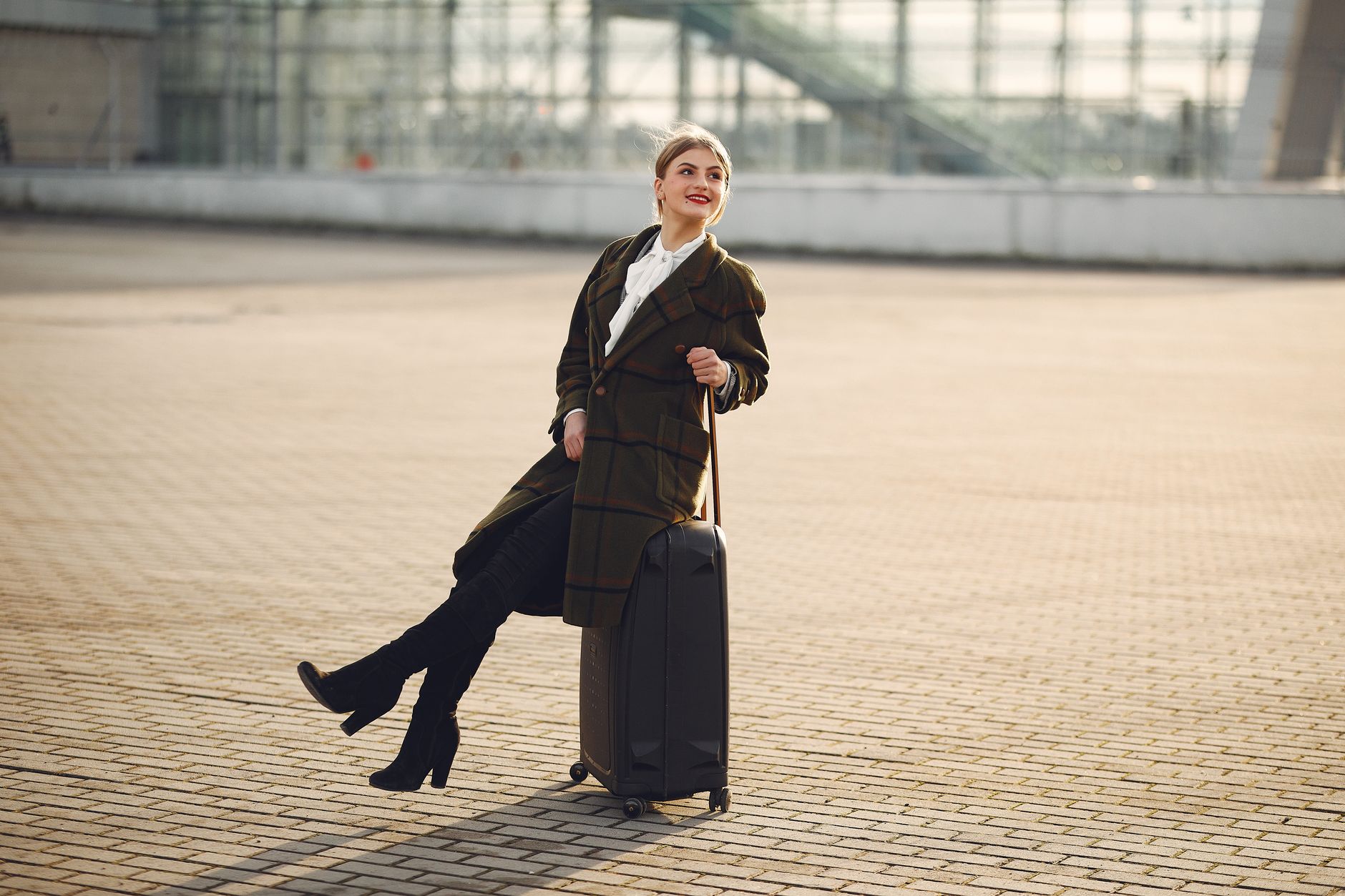 Smiling traveller with a suitcase arriving outside a terminal