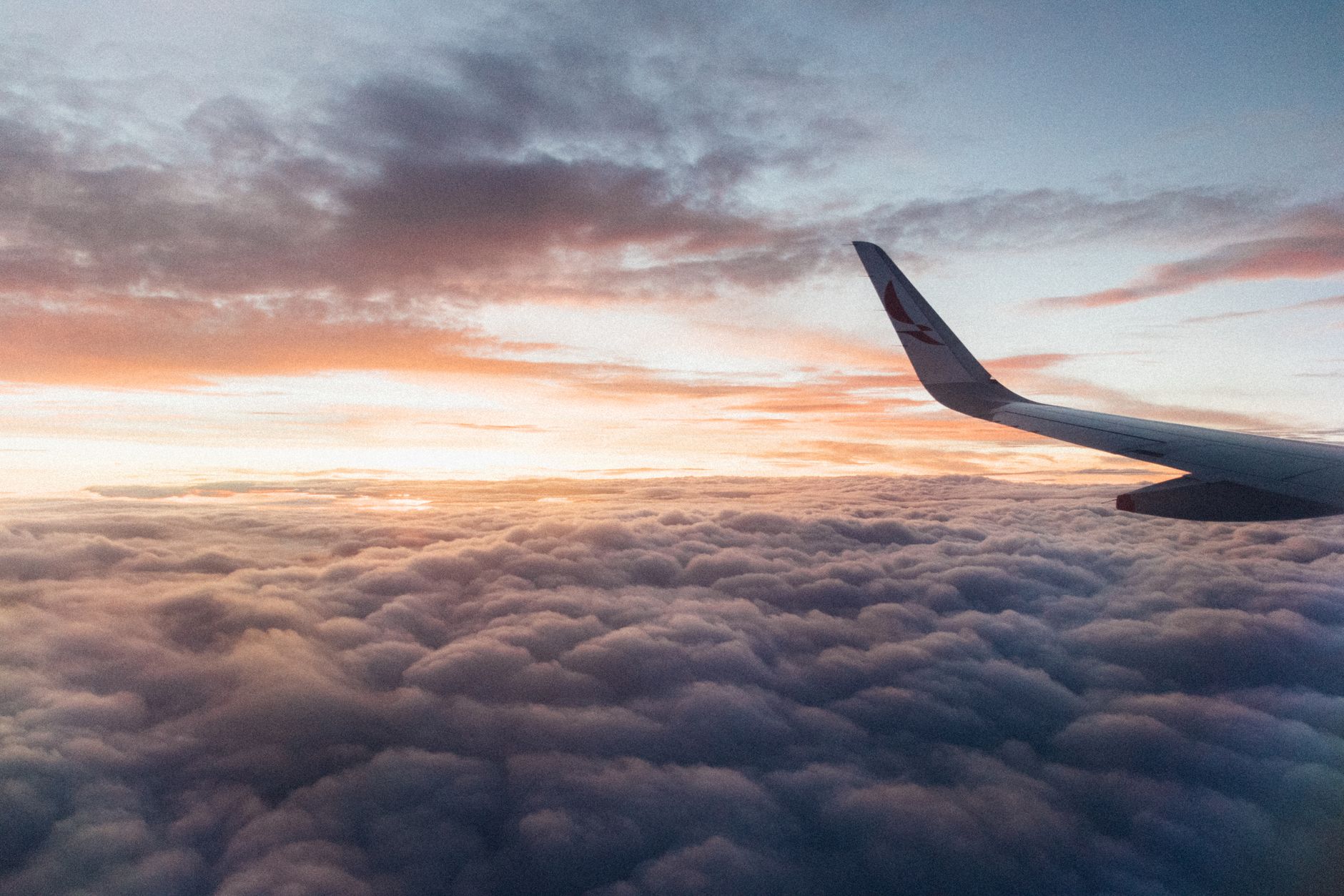 Airplane wing above golden clouds at sunset